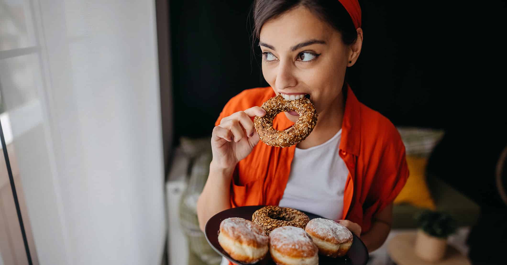 Kvinde med sukkertrang ved menstruation, der spiser donuts.