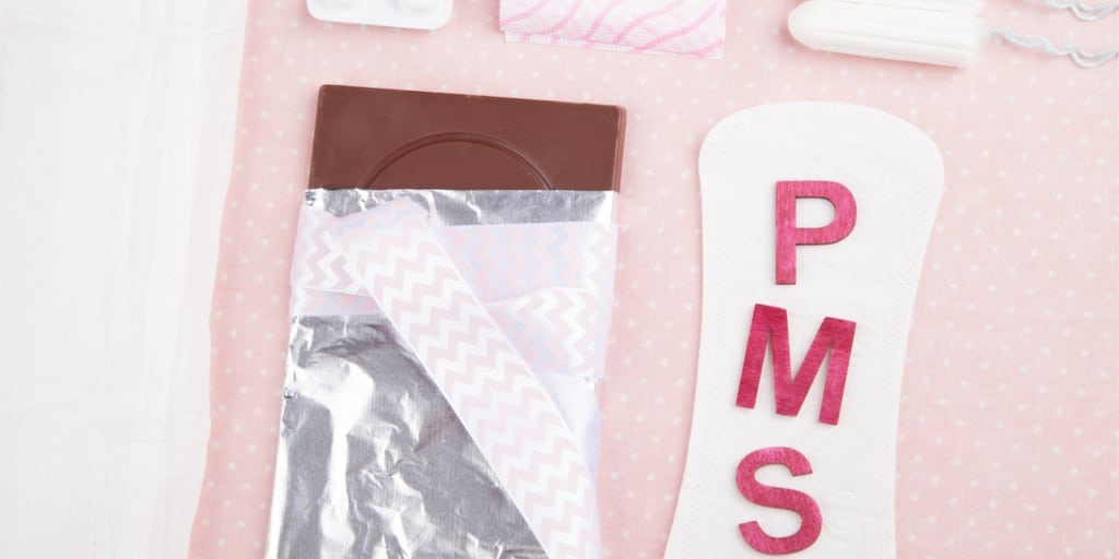 PMS-Symptomer: Billede af en chokoladebar, tamponer og bogstaverne PMS.